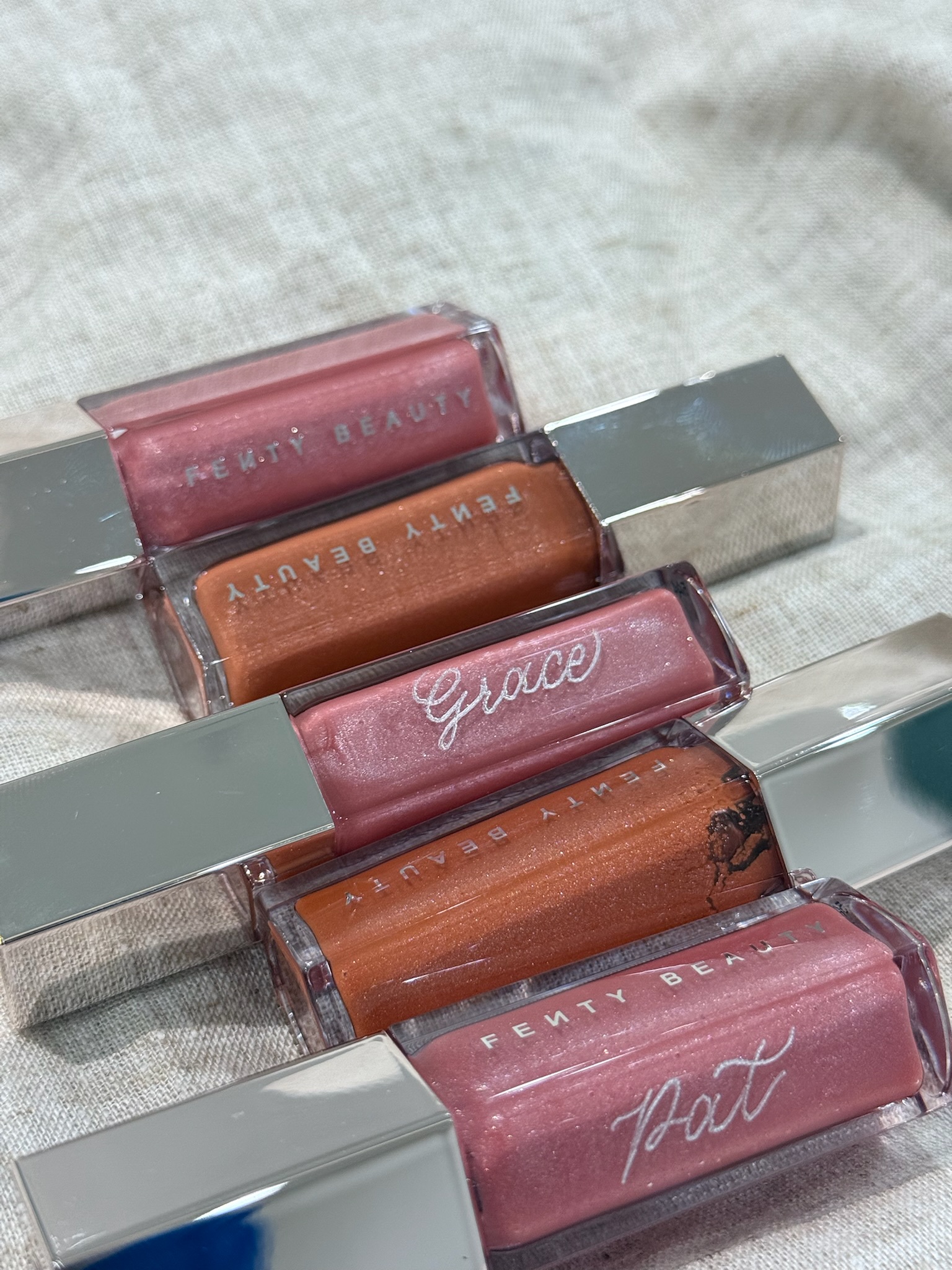 Fenty Beauty Gloss Bomb lip glosses with calligraphed names in white script