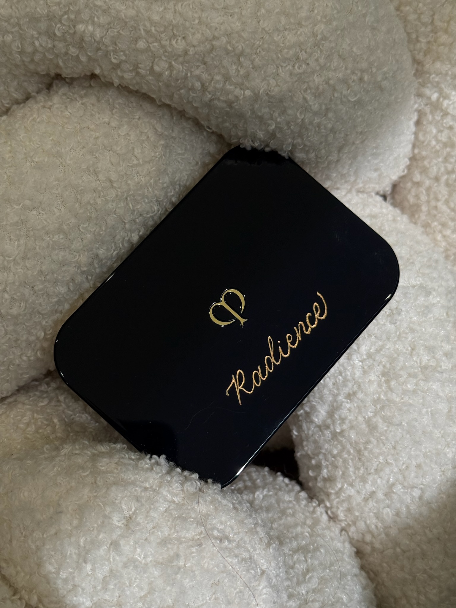 Clé de Peau Beauté black compact with gold CP logo and calligraphed name